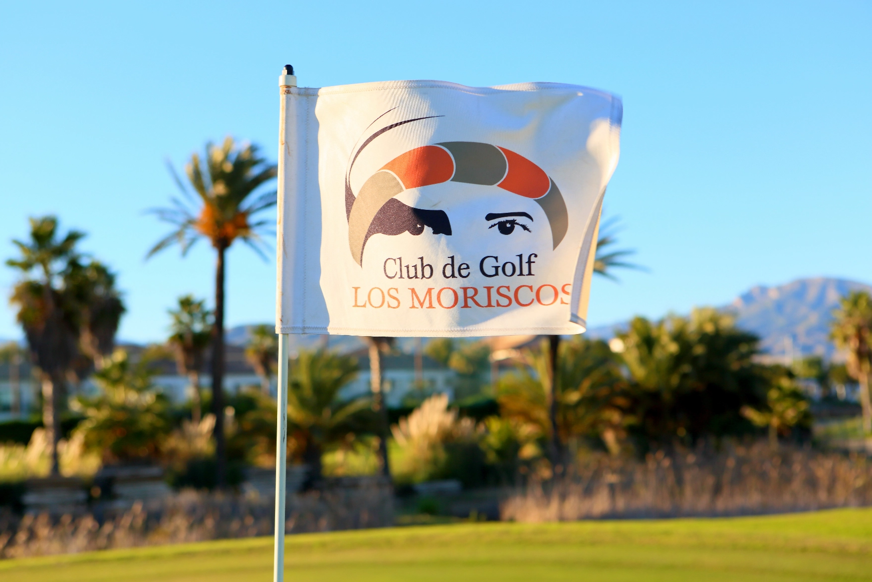 zwei Männer spielen Golf auf einem Golfplatz mit schneebedeckten Bergen im Hintergrund