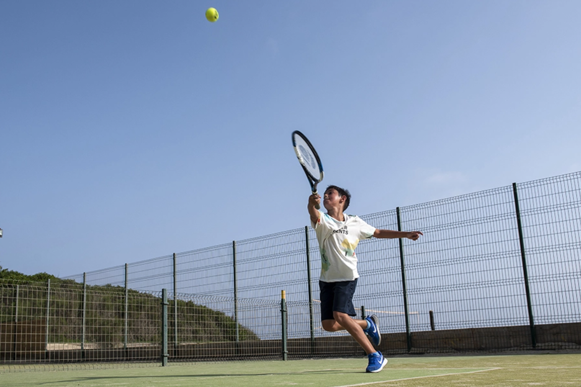 un hombre sostiene una raqueta y una pelota en una cancha de tenis