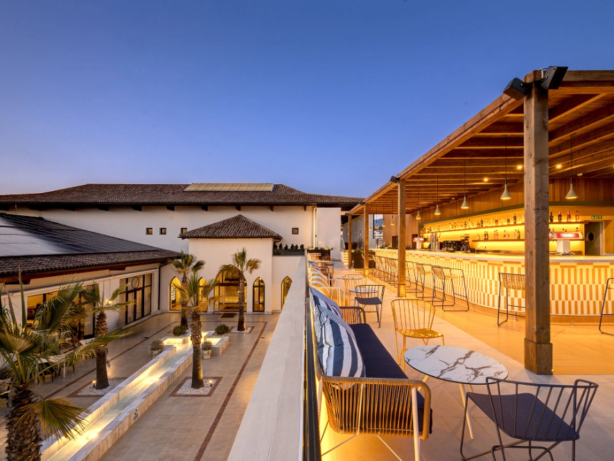 un patio con mesas y sillas y un bar al fondo
