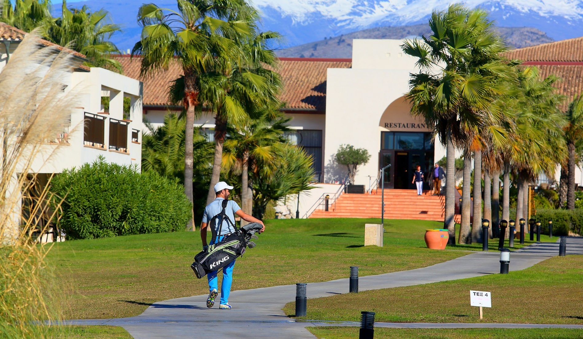 un campo de golf con montañas cubiertas de nieve en el fondo