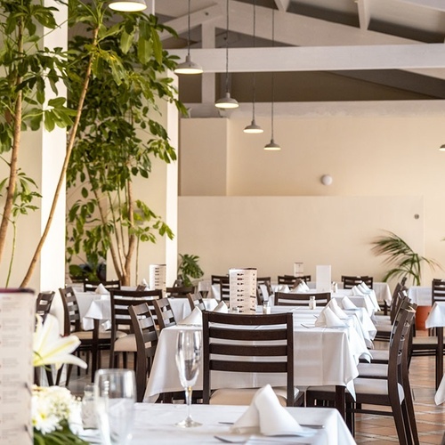 ein Raum mit weißen Tischen und Stühlen und einem Kronleuchter