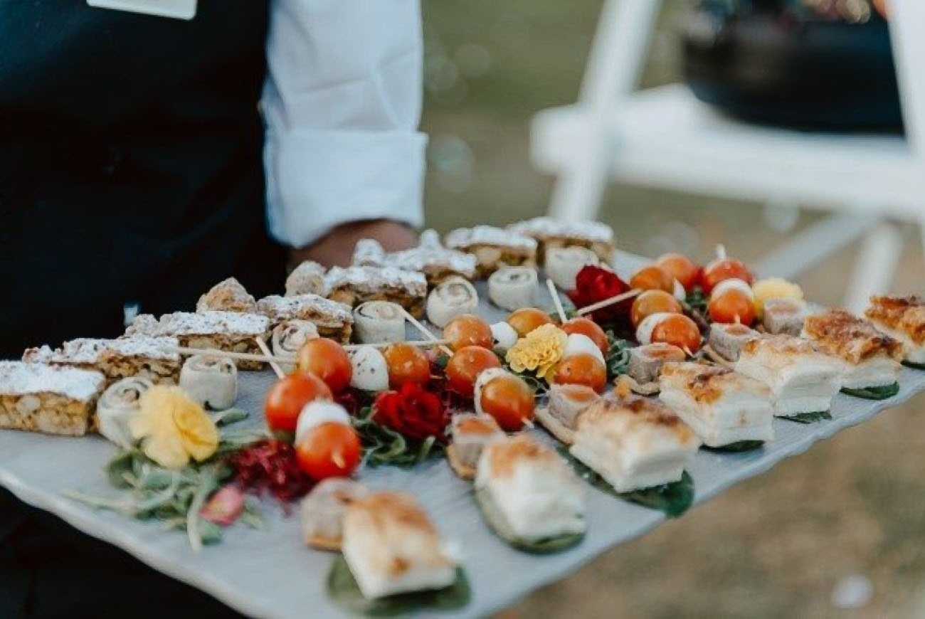 un camarero sostiene una bandeja llena de comida .