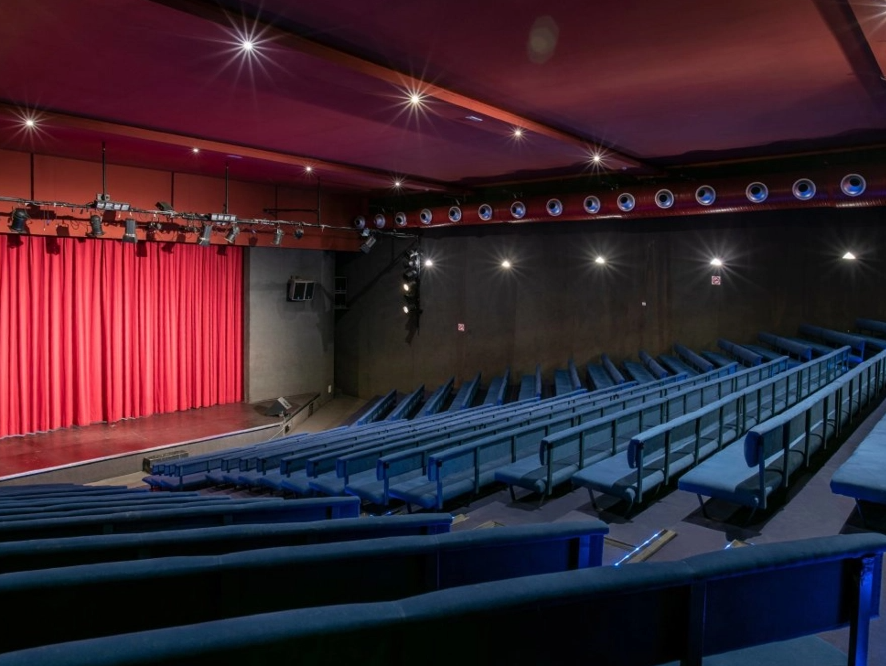 ein Theater mit blauen Sitzen und einem roten Vorhang