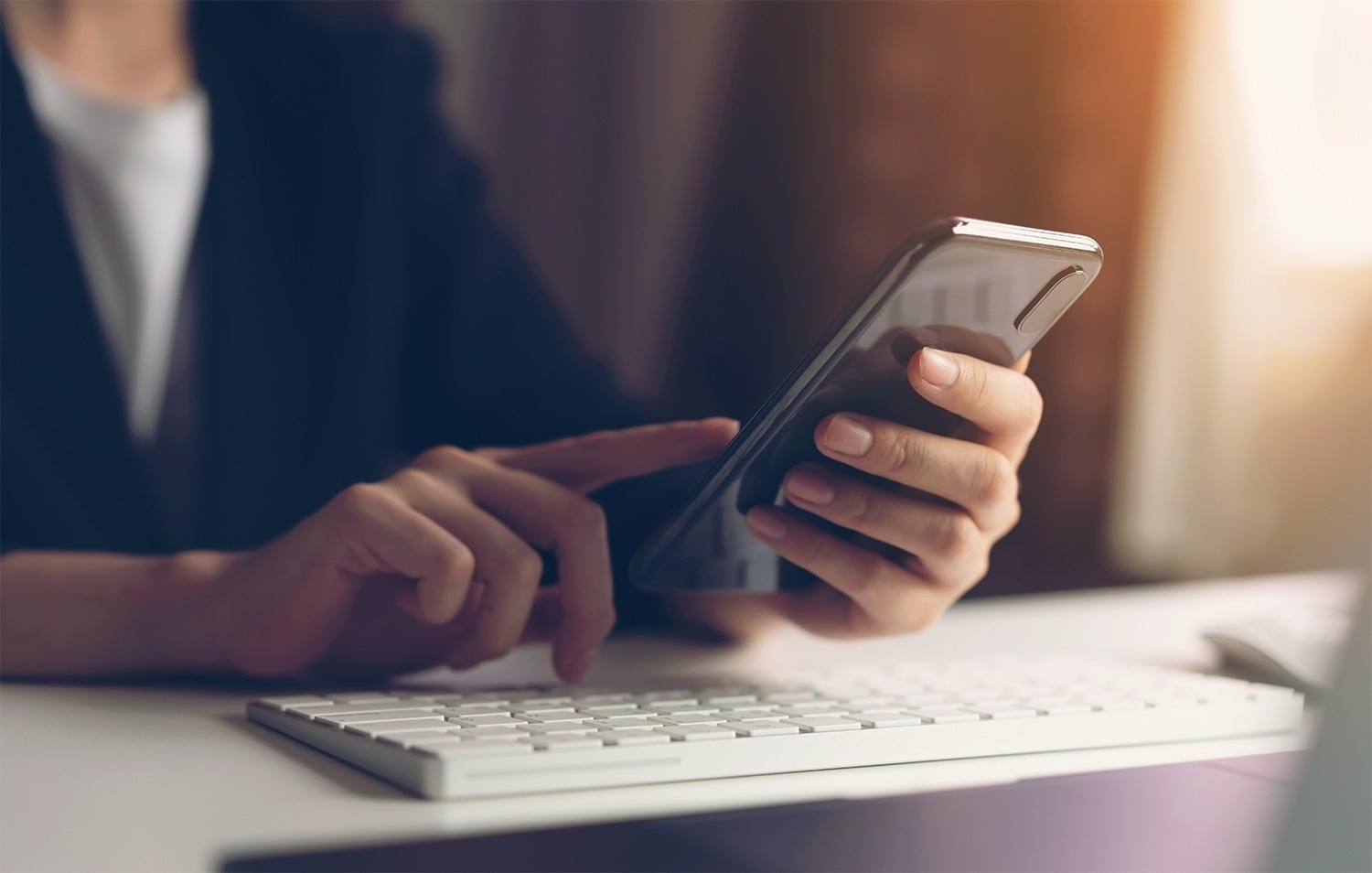 una persona sostiene un teléfono inteligente frente a un teclado