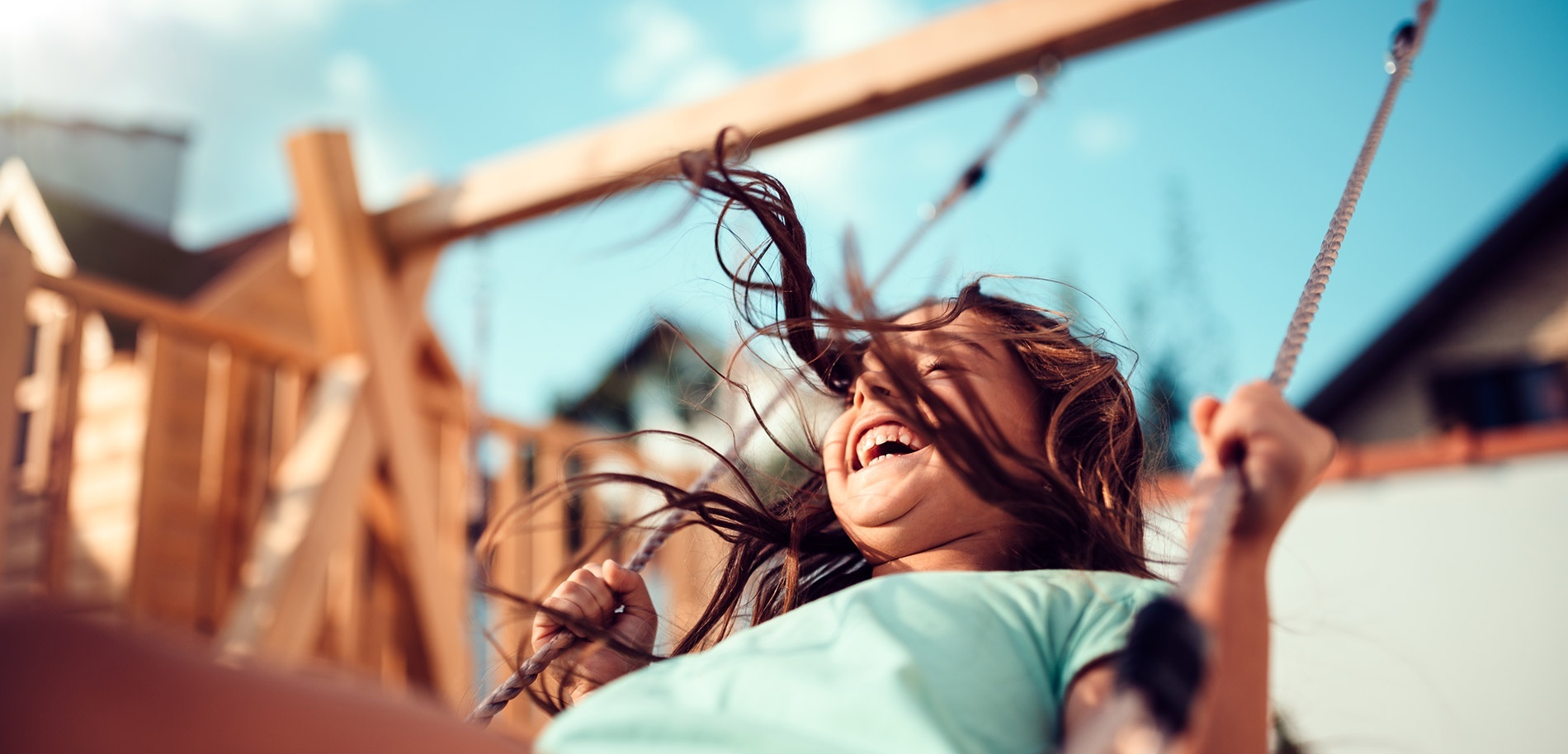 a young girl laughs while swinging on a rope swing