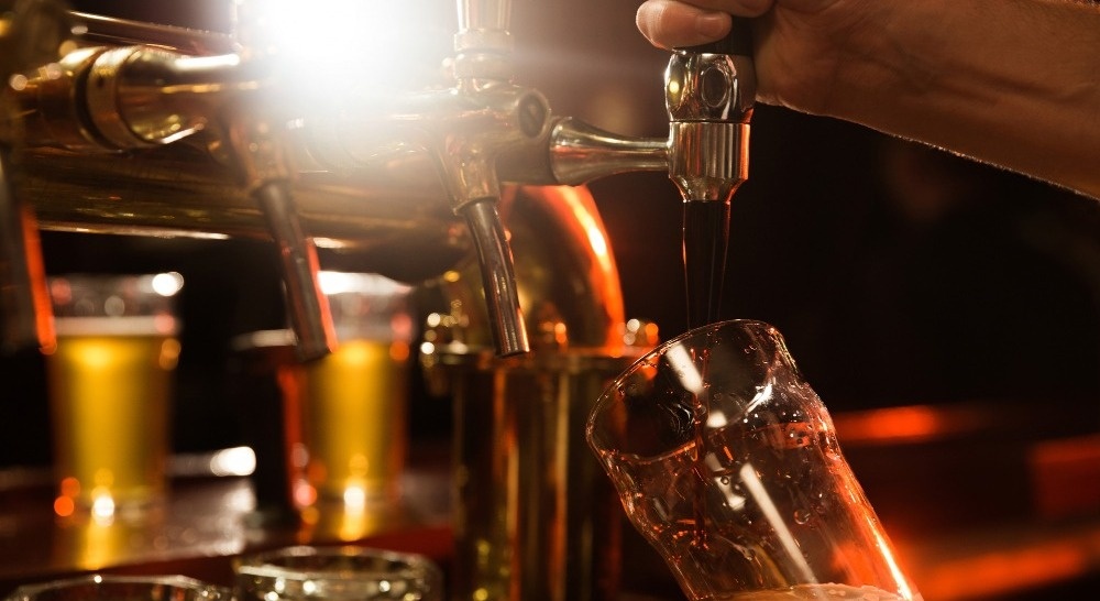 una persona está vertiendo cerveza en un vaso en un bar