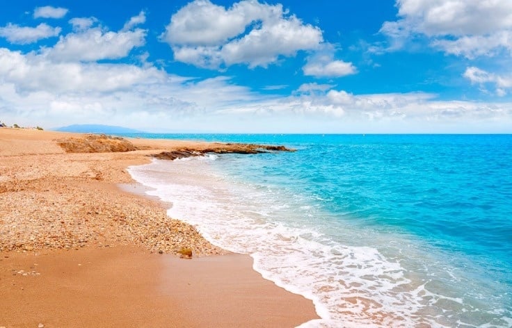 waves crashing on a sandy beach on a sunny day 