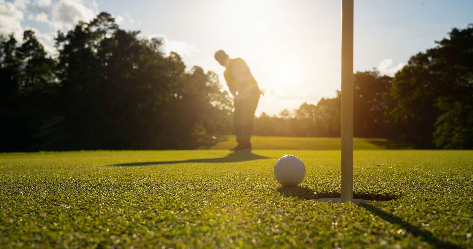 un hombre golpea una pelota de golf en un agujero en un campo de golf