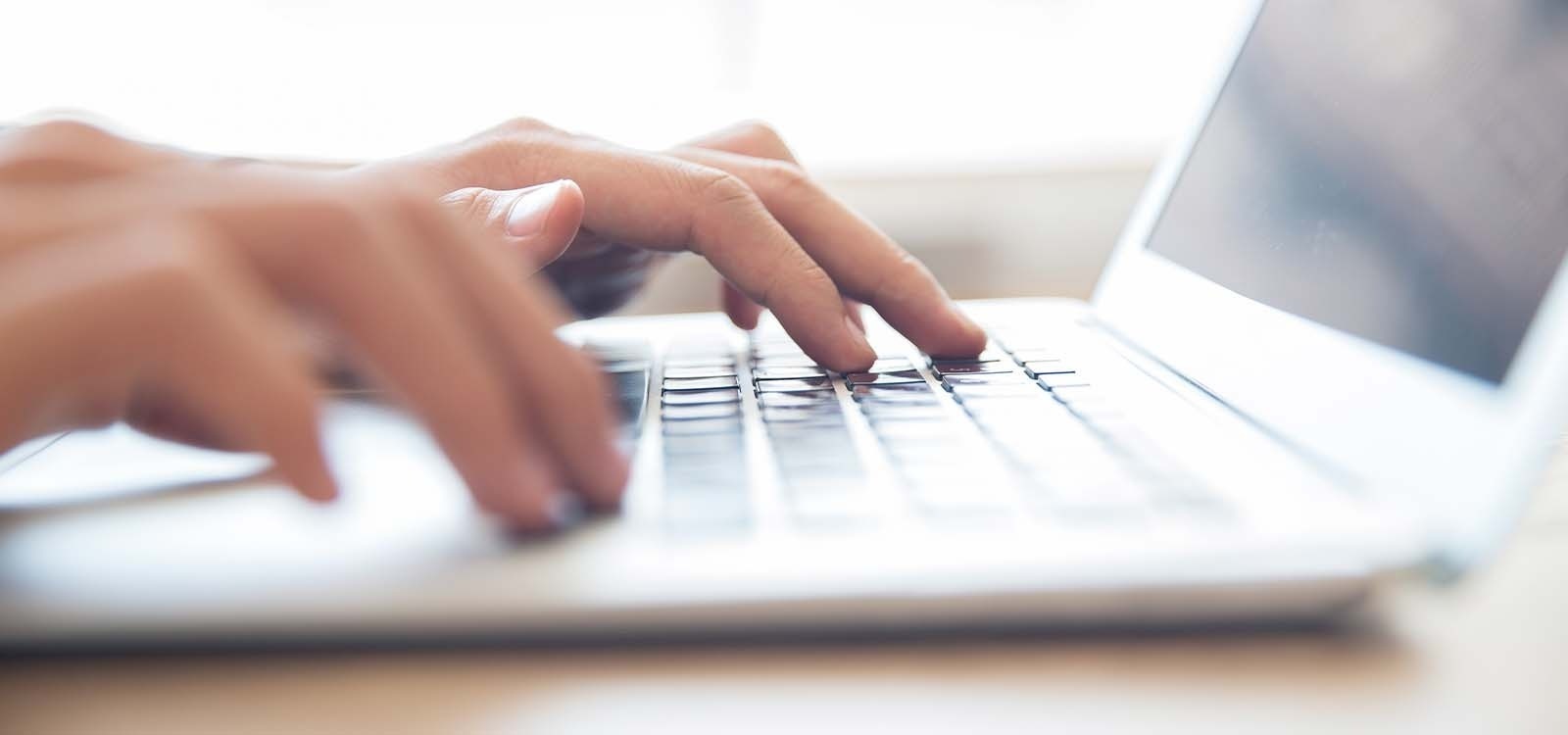 una persona está escribiendo en un teclado de computadora portátil