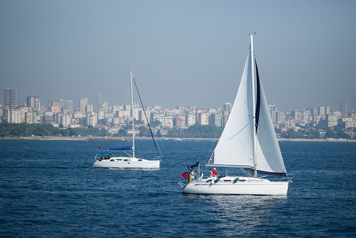 two sailboats in the ocean with a city in the background