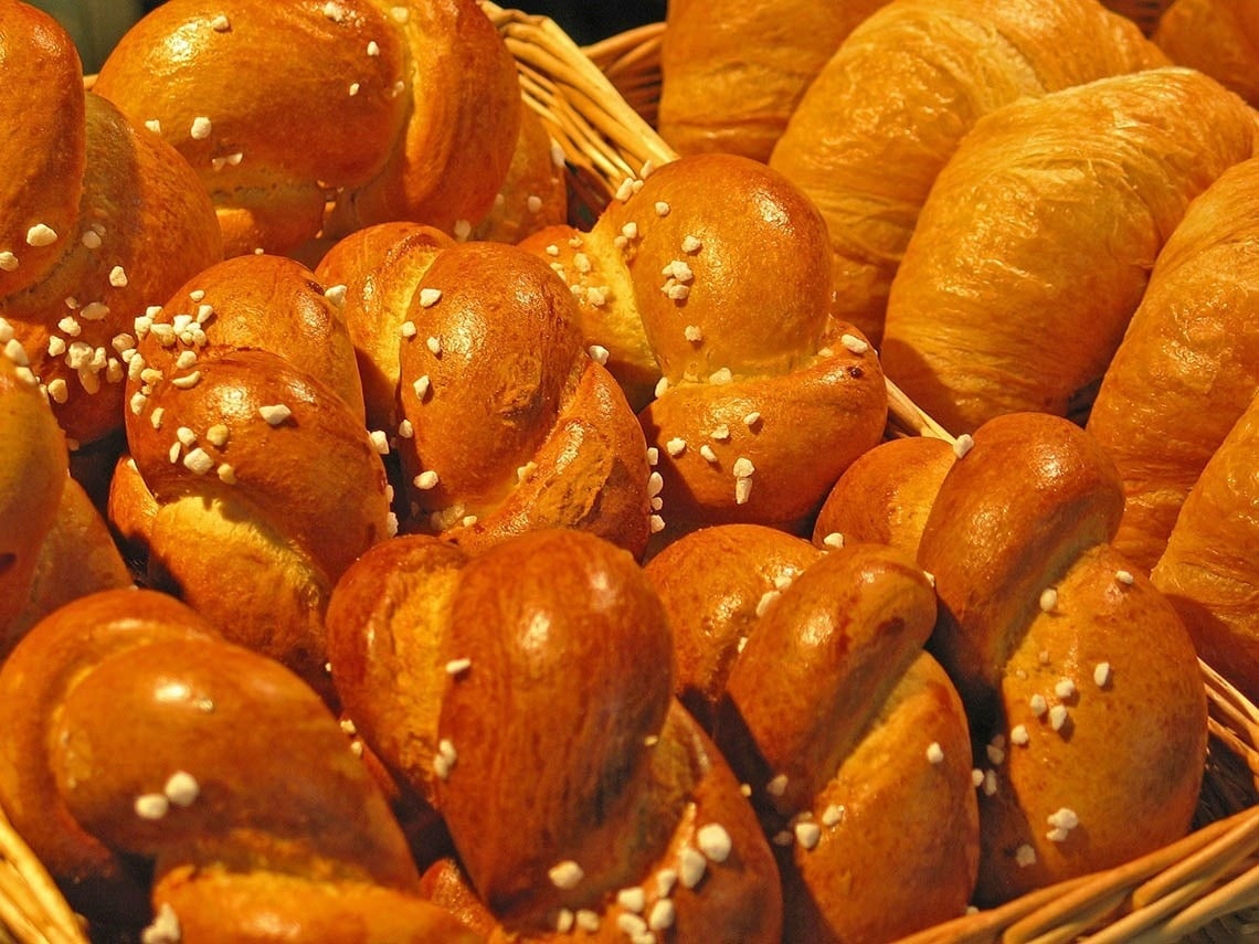un montón de panes y croissants en una canasta de mimbre