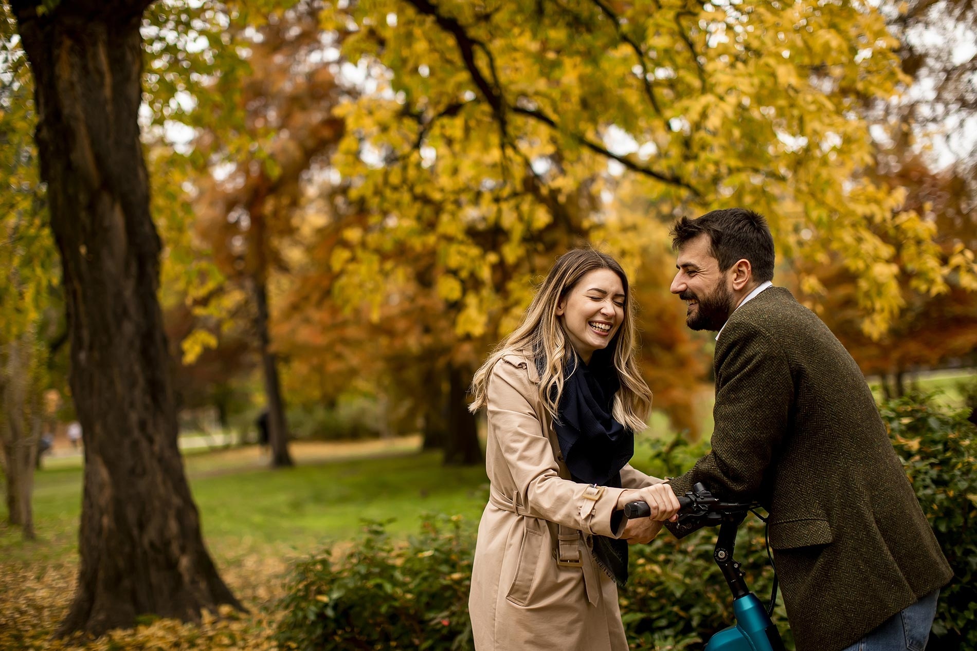 a man and a woman are laughing in a park