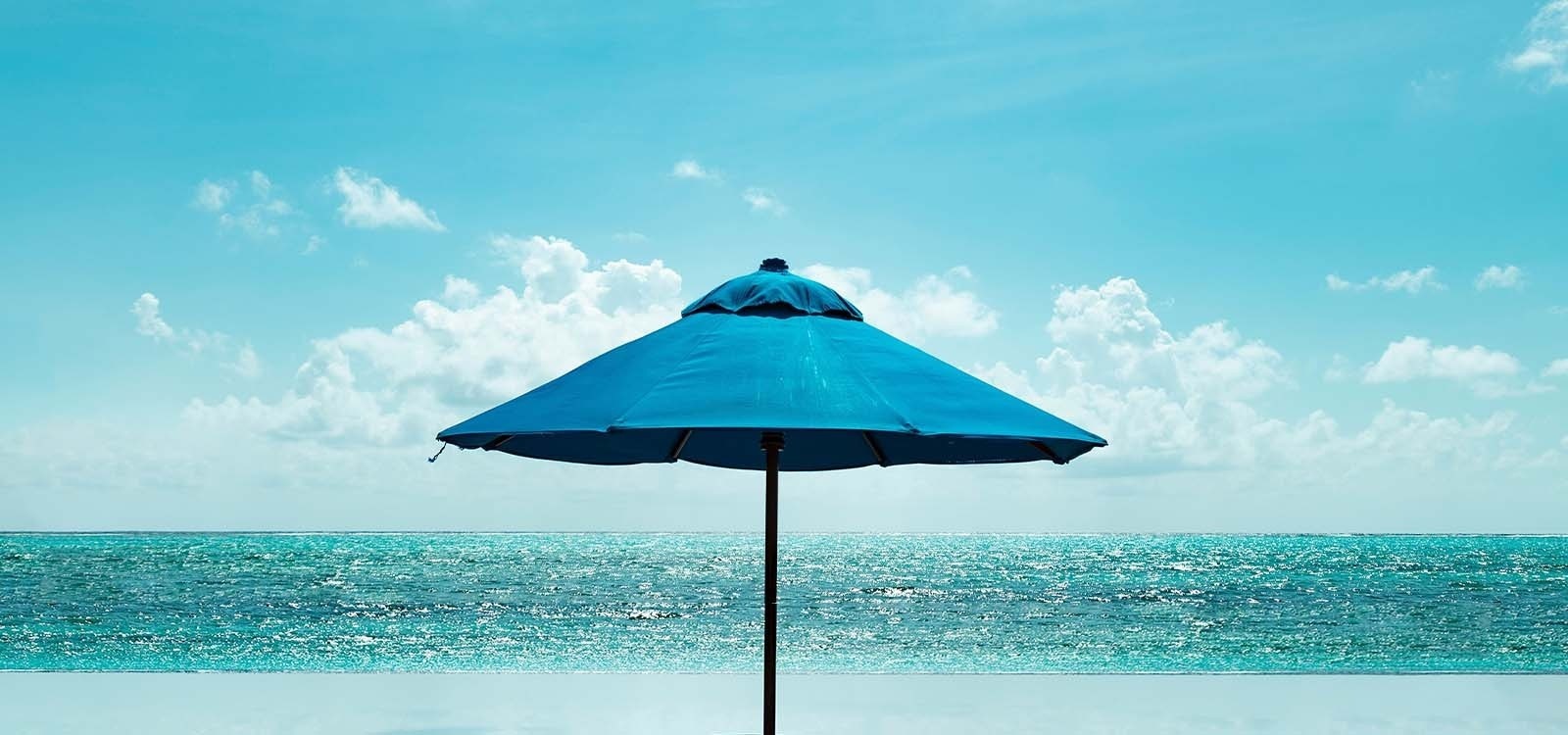 un paraguas azul está en la playa frente al océano