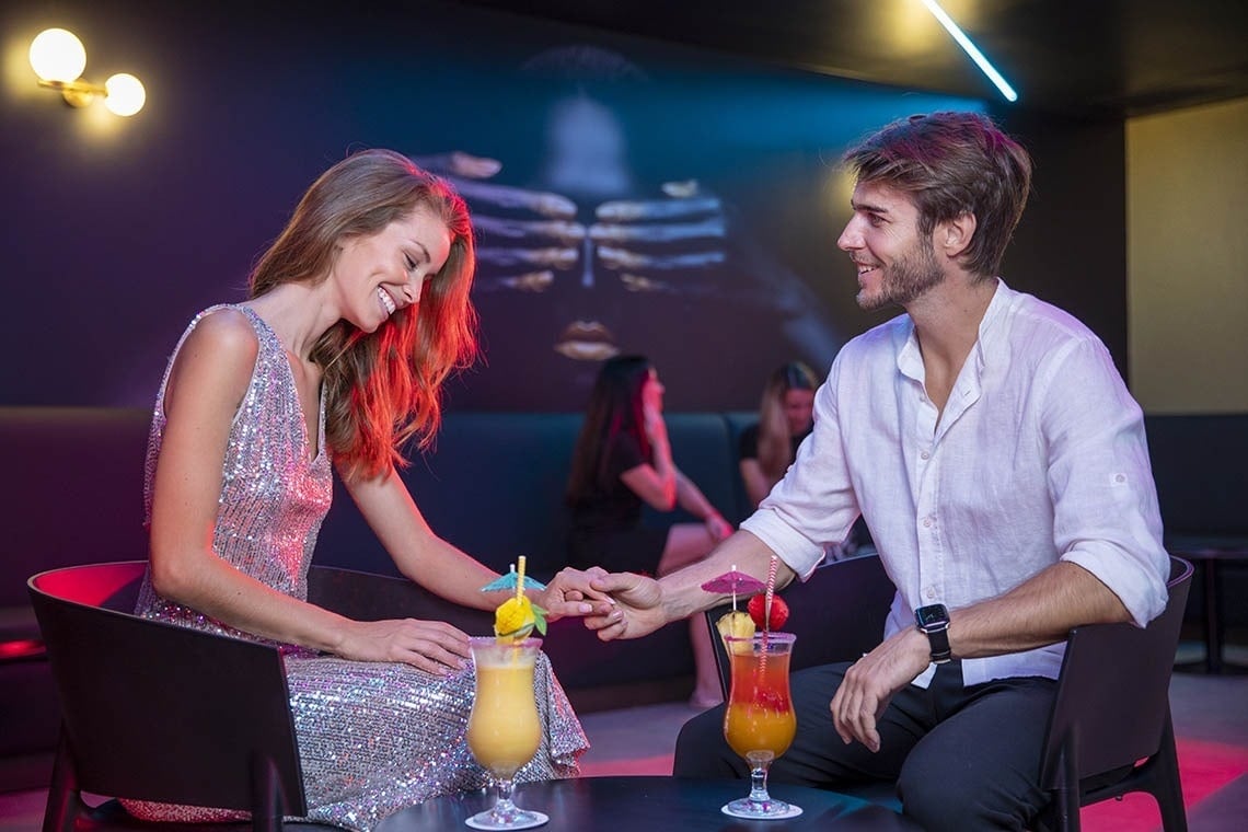 un hombre y una mujer están sentados en una mesa con bebidas