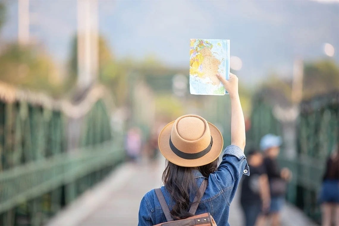 a woman in a hat is holding up a map of the world