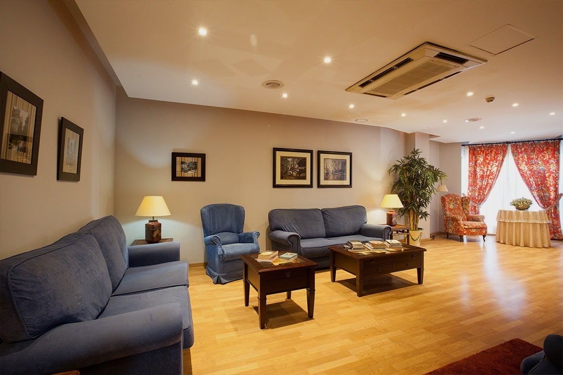 a room with chairs and a table with a picture of a chandelier on the wall