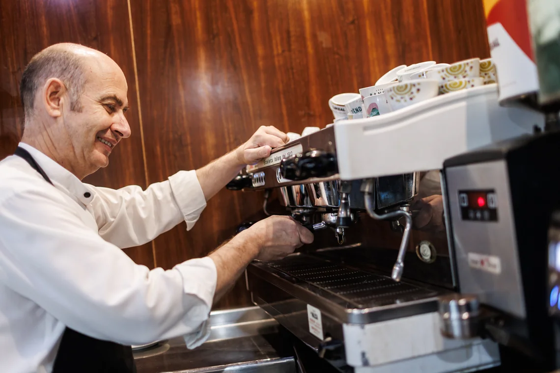 Barista sonriente preparando café en máquina profesional. Hotel Acosta Ciudad de la Música