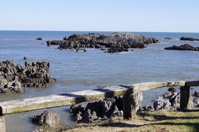 a wooden railing overlooking a body of water with rocks in the background - 