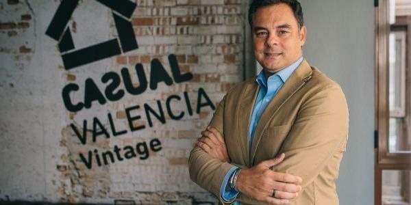 un hombre con los brazos cruzados está parado frente a una pared de ladrillos .