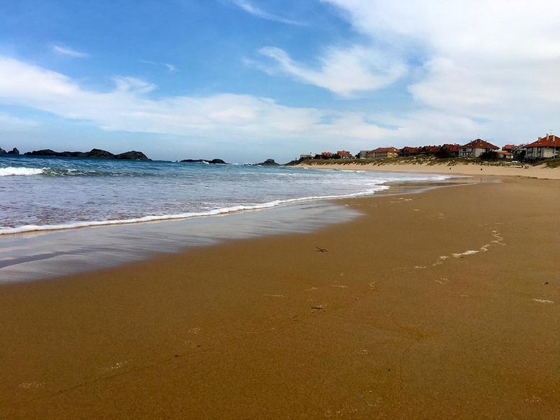 a beach with houses in the background and a blue sky