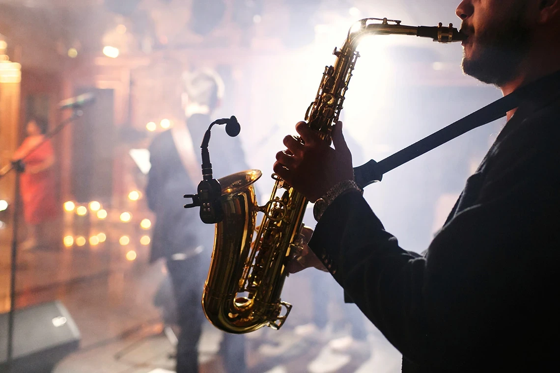 Músico tocando saxofón en ambiente festivo, ideal para eventos Hotel Acosta Ciudad de la Música.