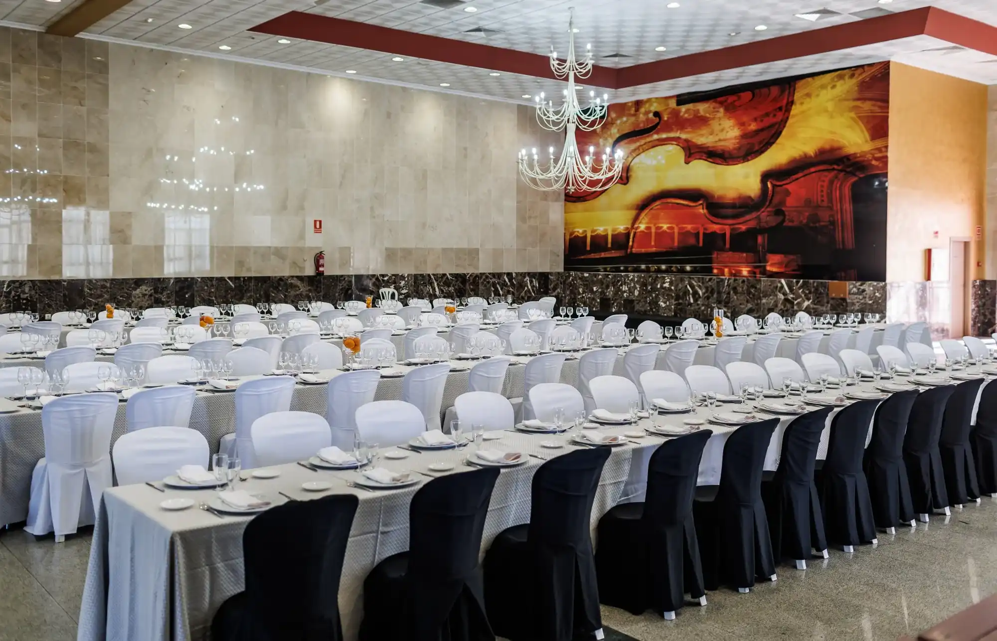 Mesa de hotel con copas y cubiertos. Fondo con arte musical Acosta: Ciudad de la Musica.