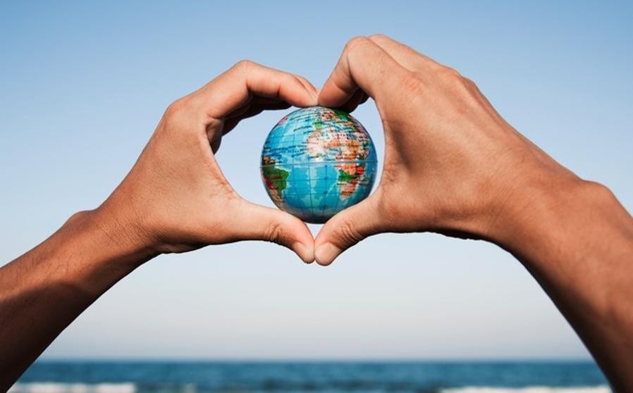 duas mãos fazem um coração com um globo