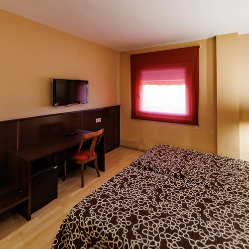 Cozy hotel room with a comfortable bed, desk, and window view. Hotel Acosta Ciudad de la Música