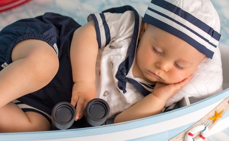 a baby in a sailor outfit is sleeping in a boat