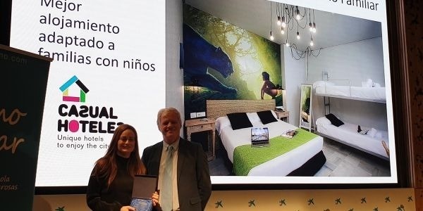 un hombre y una mujer están parados frente a una pantalla con una imagen de una habitación de hotel .