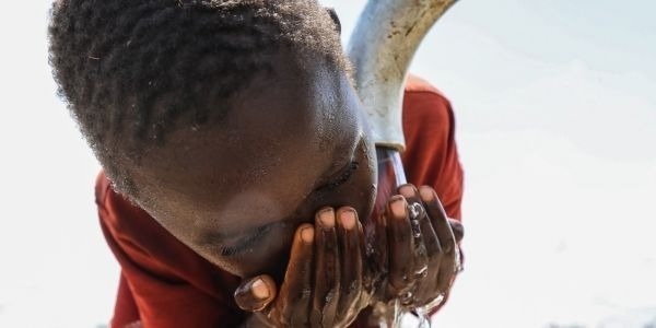 un niño está bebiendo agua de un pozo de agua .