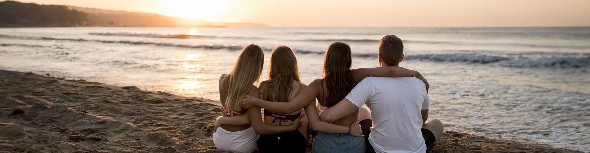 a group of people sitting on the beach looking at the ocean