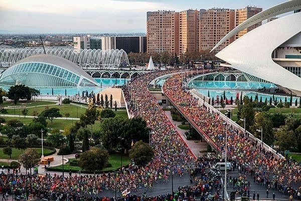 una gran multitud de personas corre por una carretera en una ciudad .