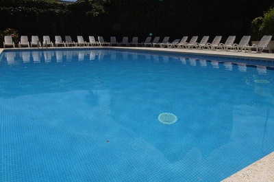una piscina con agua azul y sillas blancas alrededor - 