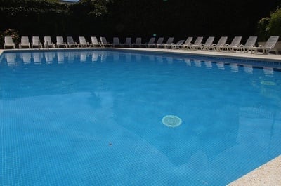 una piscina con agua azul y sillas blancas alrededor - 