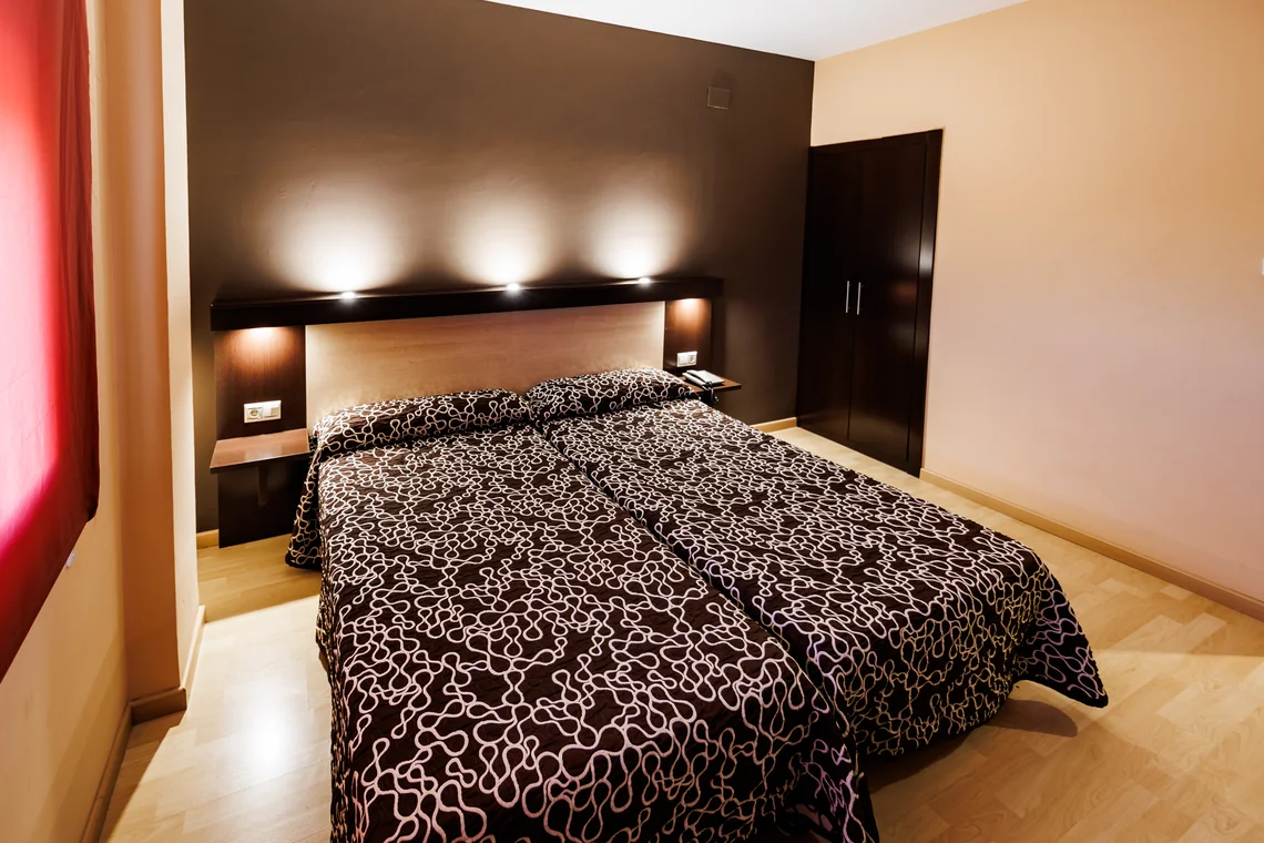 Habitación de hotel con cama matrimonial Hotel Acosta Ciudad de la Música, sofá y decoración moderna.