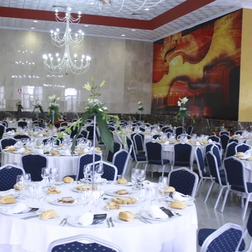 Elegant ballroom set for a banquet Hotel Acosta Ciudad de la Música with round tables and chandeliers.