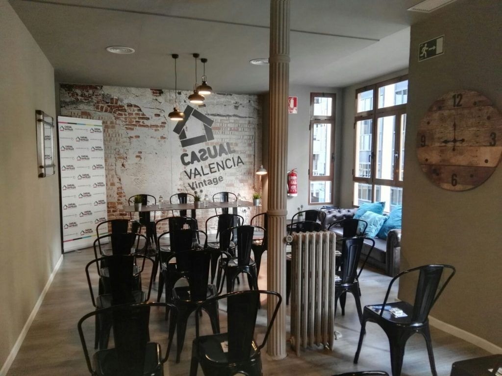 una habitación llena de sillas y mesas con una pared que dice casual valencia vintage