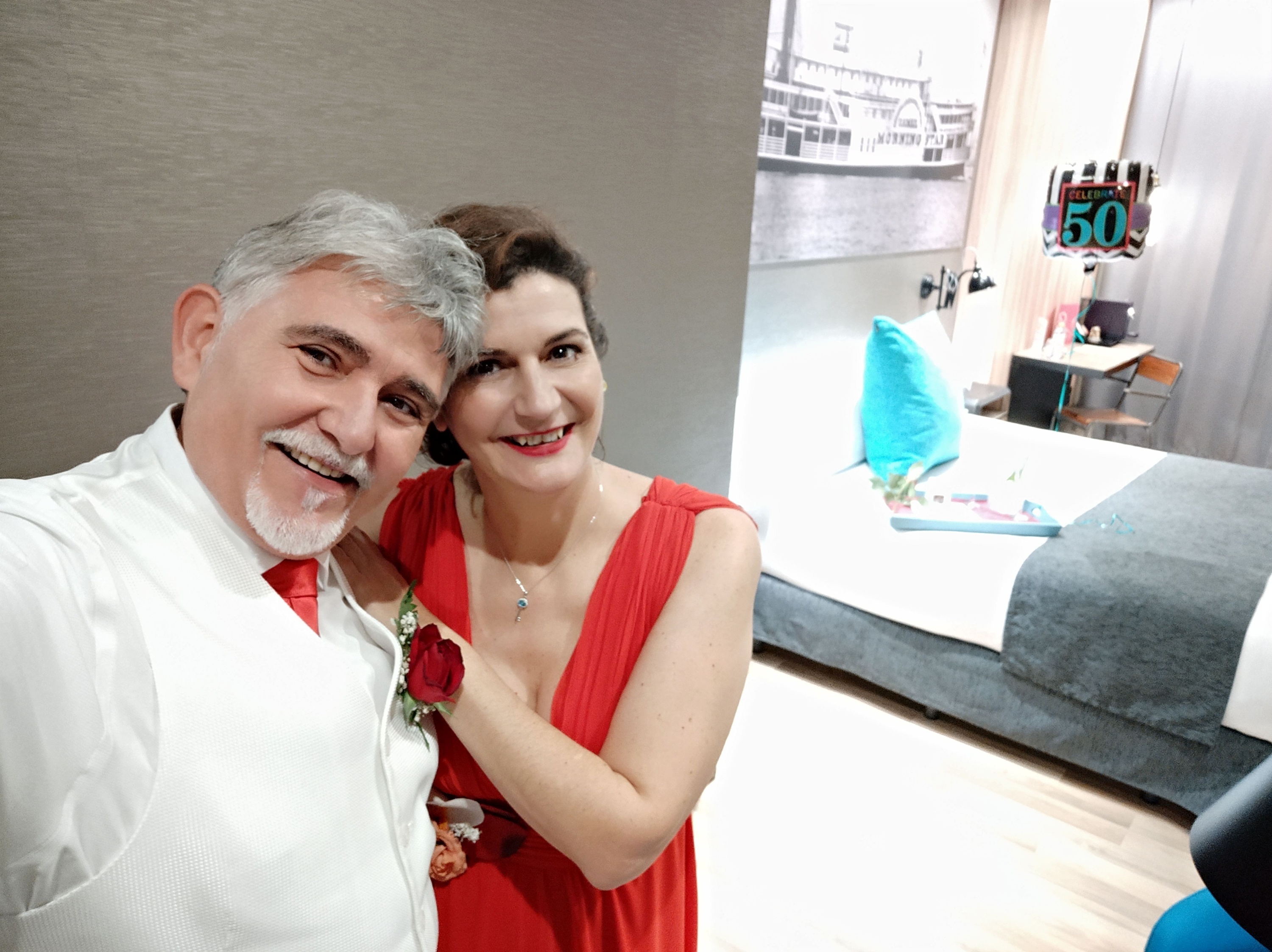 un hombre y una mujer posan para una foto en una habitación con un cartel que dice 50