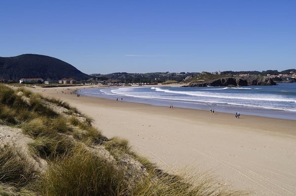 un grupo de personas camina por la playa en un día soleado