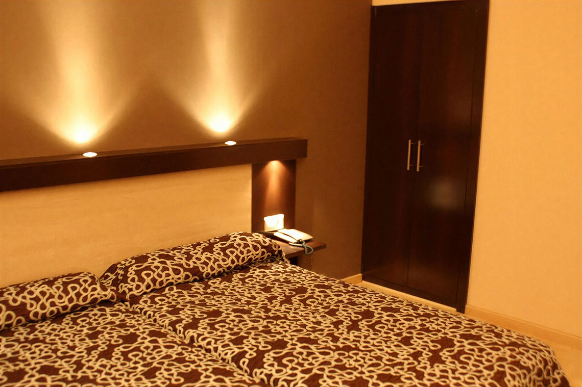 Habitación de hotel con cama doble, armario oscuro y luces empotradas. Hotel Acosta Ciudad de la Música