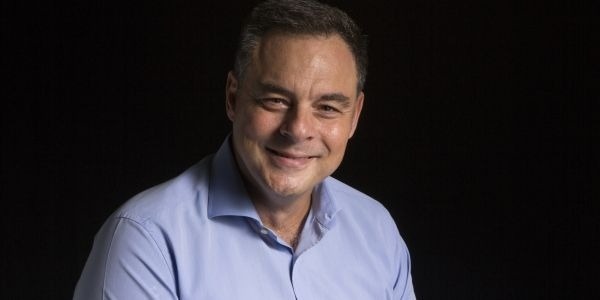 un hombre con una camisa azul está sonriendo y mirando a la cámara .