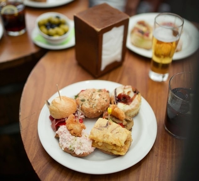 a plate of food sits on a table next to a glass of beer