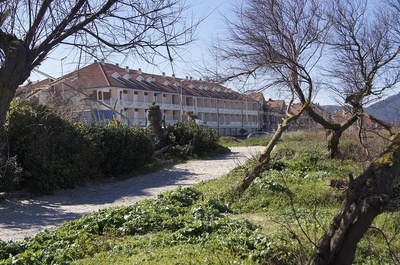 a row of houses with red roofs are behind a dirt path - 