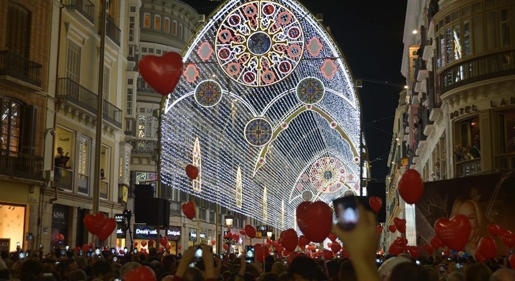 una gran multitud de personas sostiene globos rojos en forma de corazón
