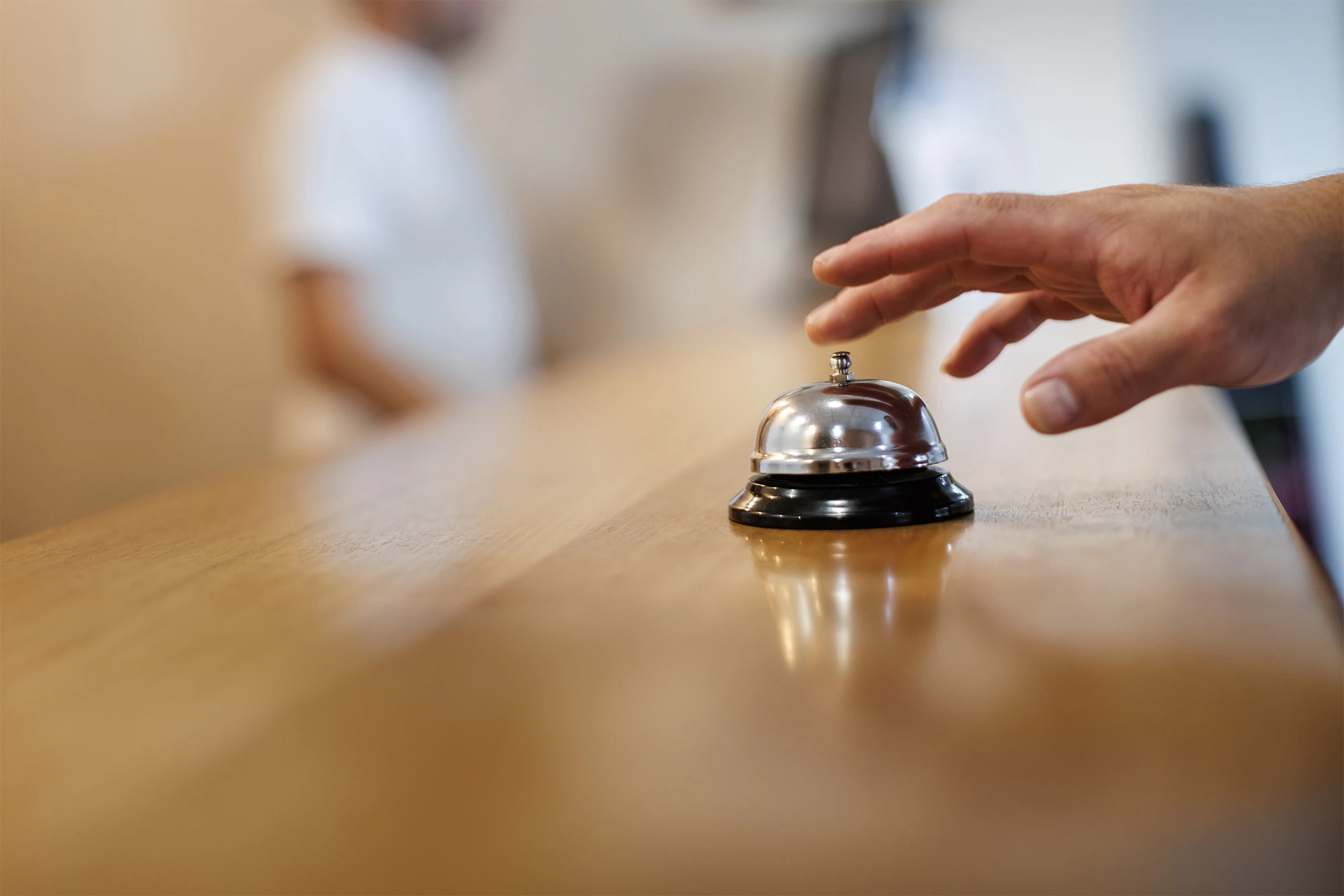 Hand rings desk bell at hotel check-in. Hotel Acosta Ciudad de la Música