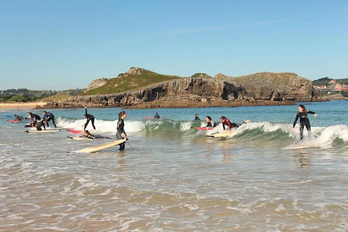 un grupo de surfistas están surfeando en la playa