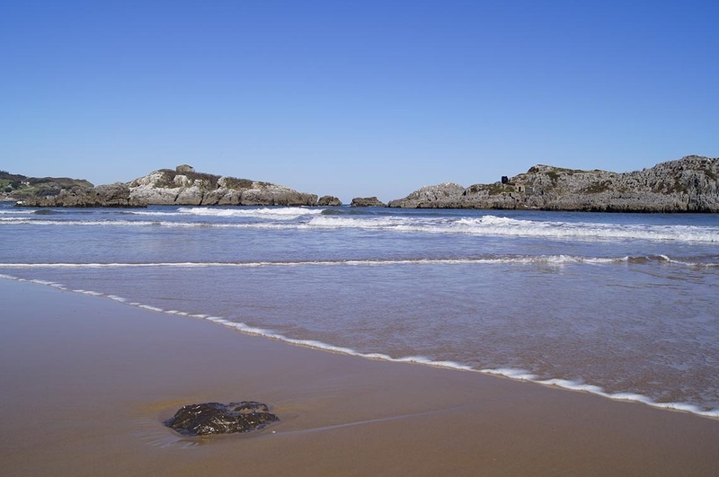 una playa con una gran roca en la arena