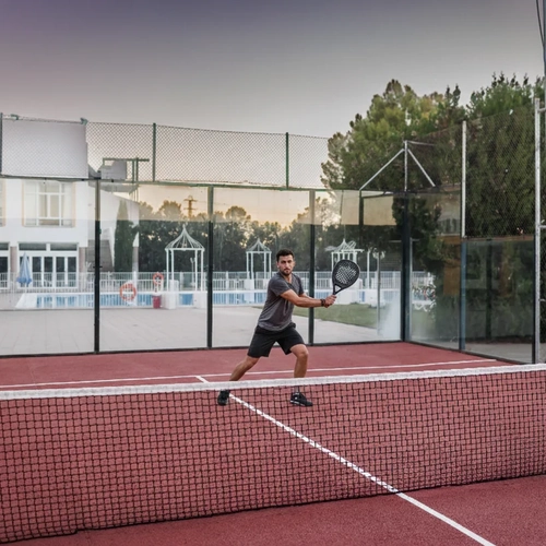 Man playing padel tennis on a court near hotel amenities Hotel Acosta Ciudad de la Música.