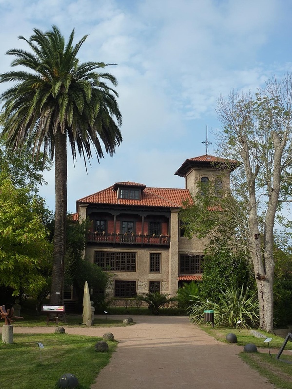 a large building with a red tile roof is surrounded by palm trees